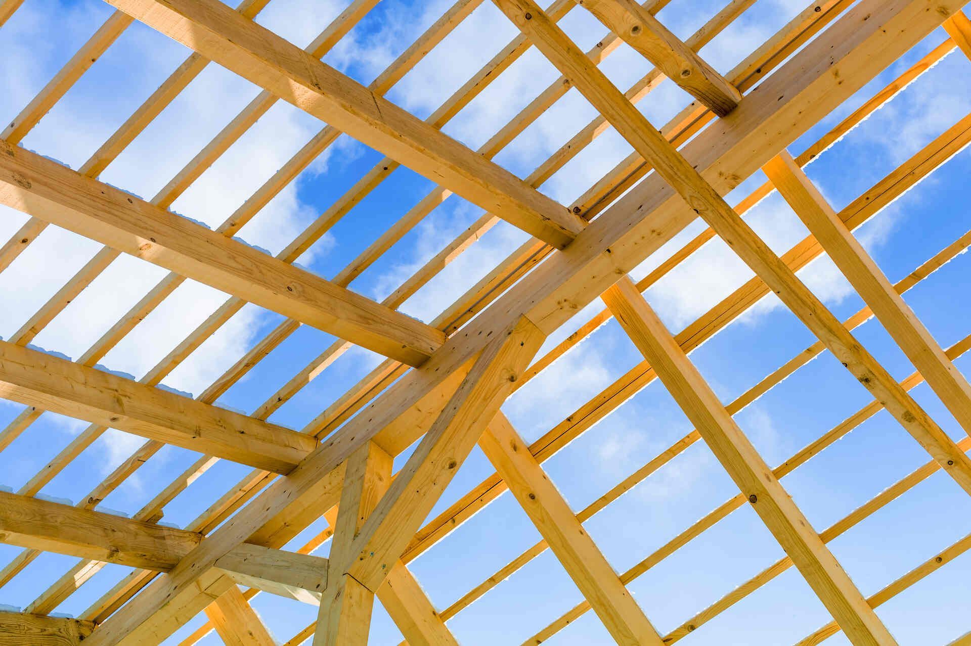 Ein im Bau befindliches Holzdach mit einem blauen Himmel im Hintergrund.