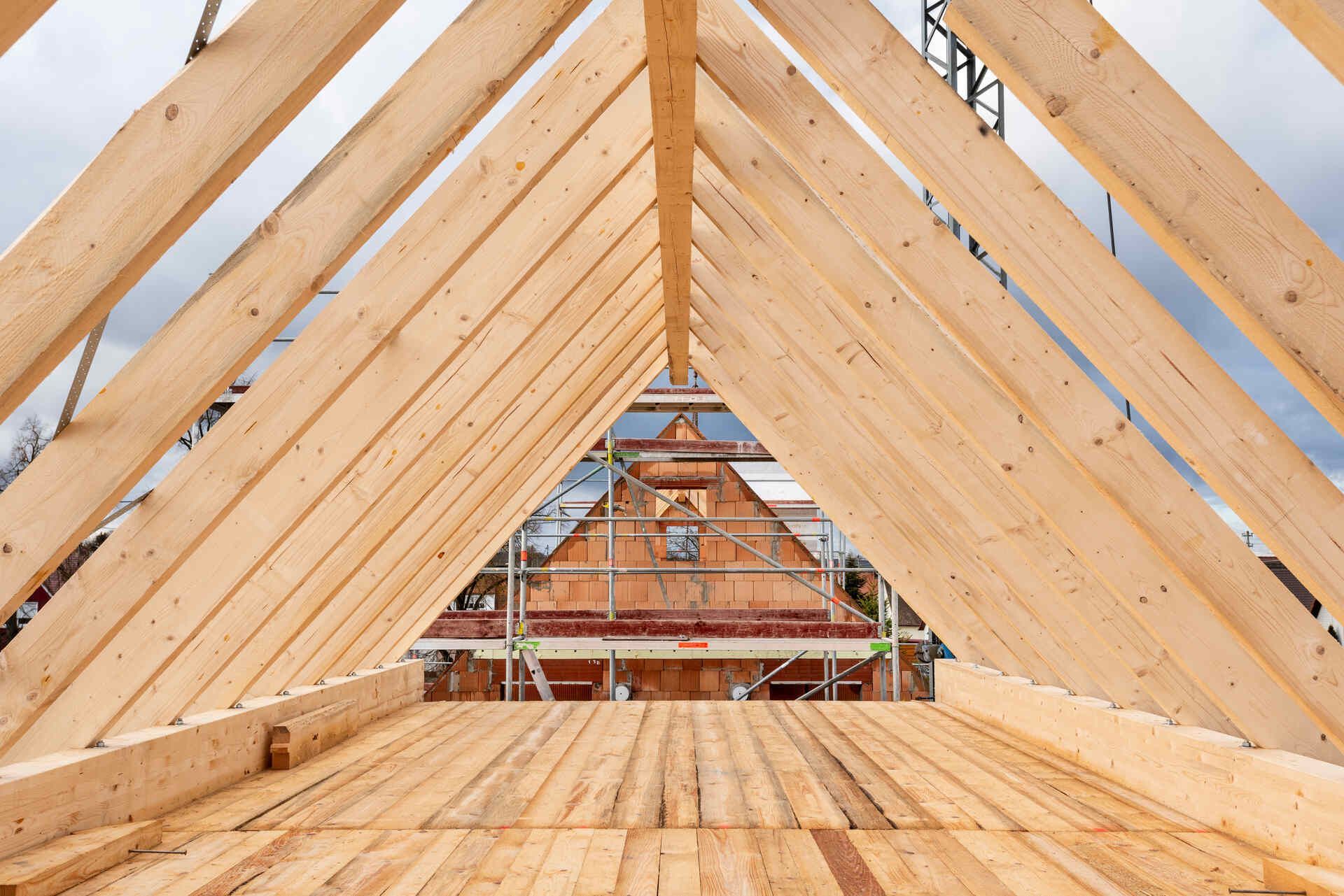 Das Dach eines Hauses wird mit Holzbalken gebaut