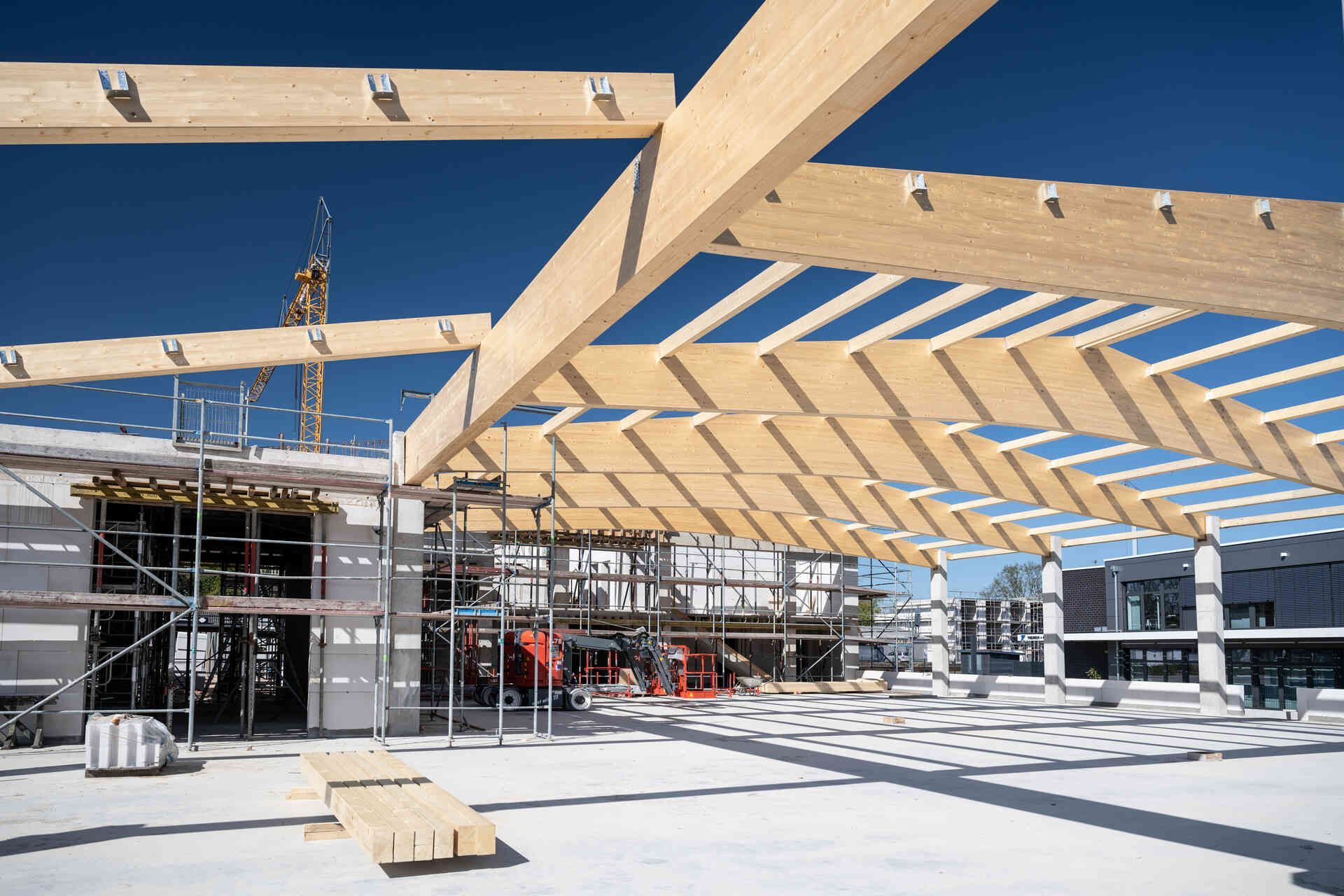 Auf einem Gebäude wird eine große Holzkonstruktion errichtet.
