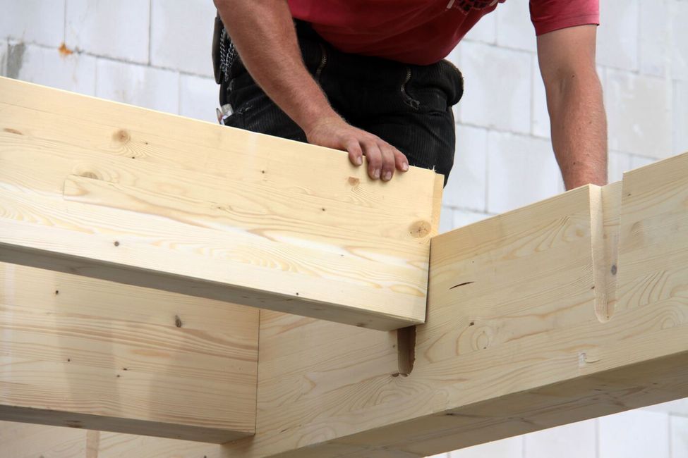 Ein Mann steht auf einem Holzbalken.