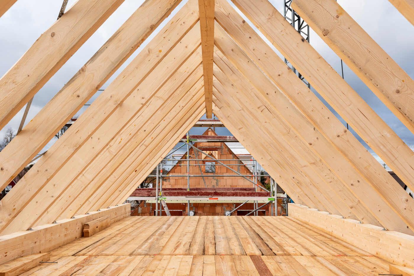 Das Dach eines Hauses wird mit Holzbalken gebaut.