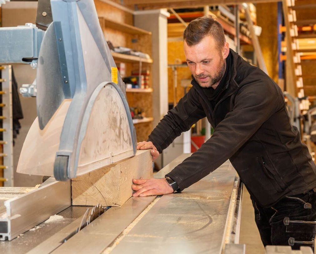 Ein Mann schneidet mit einer Kreissäge ein Stück Holz.