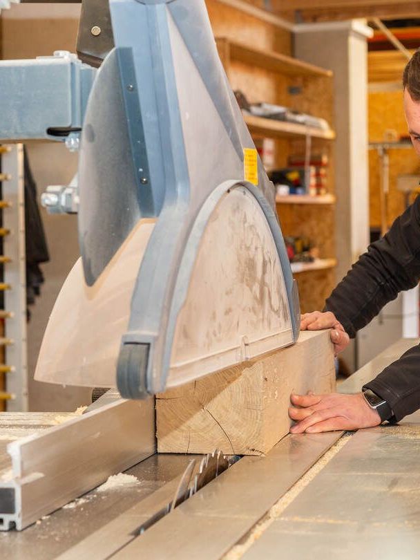 Ein Mann schneidet ein Stück Holz auf einer Tischkreissäge.