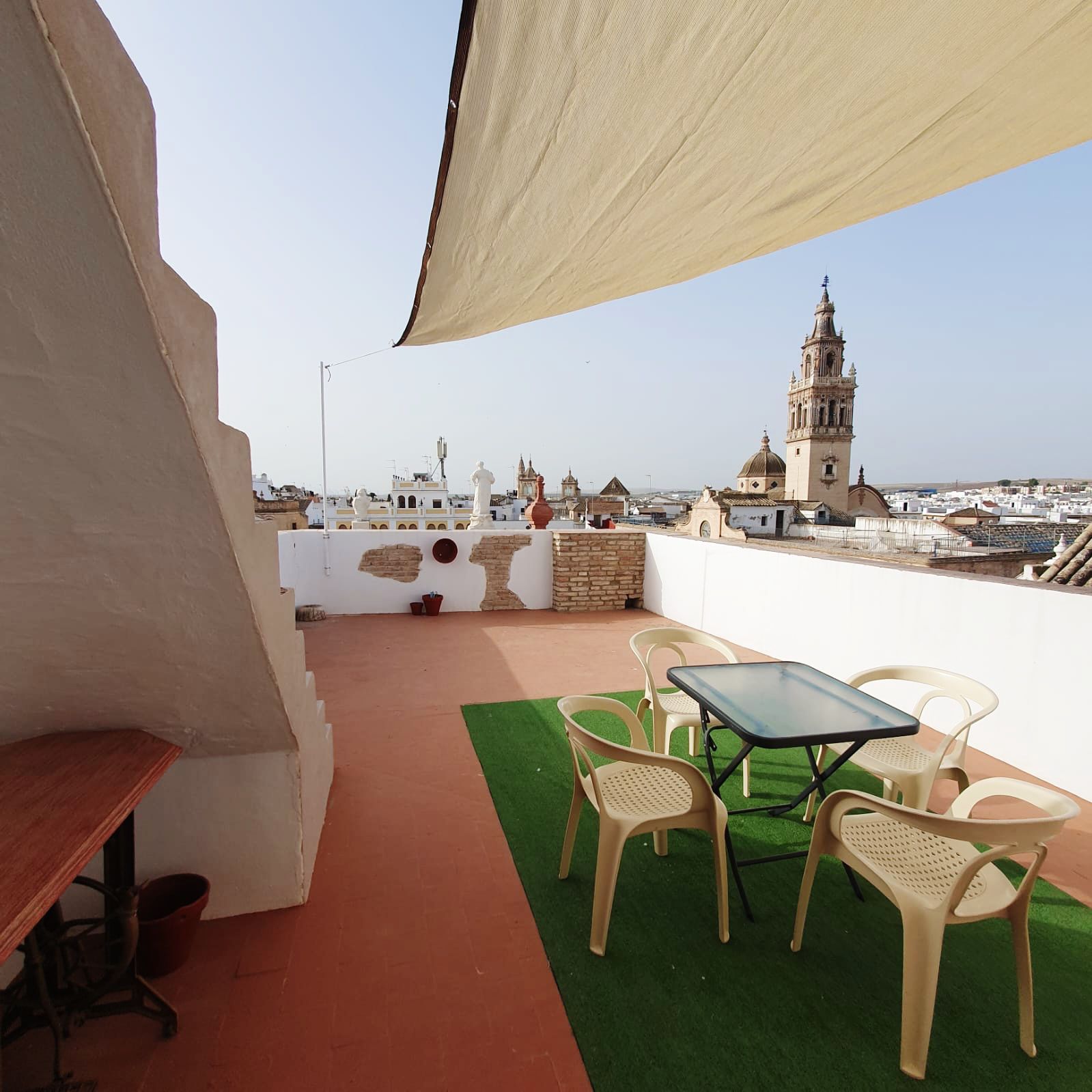 Una mesa y sillas en una azotea con una torre de reloj al fondo.