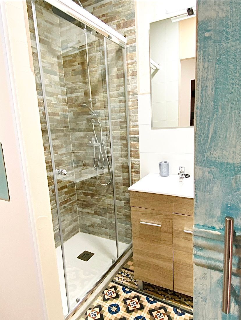 Un baño con lavabo, ducha y espejo.