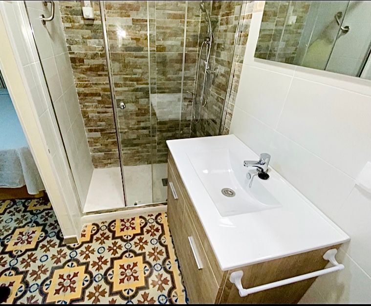 Un baño con lavabo, espejo y ducha.