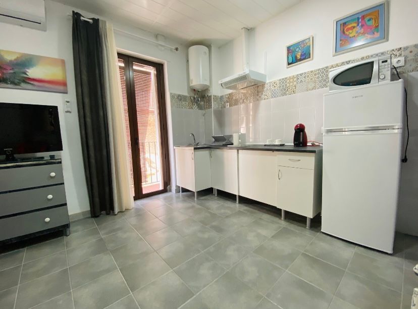 Una cocina con frigorífico, microondas, fregadero y televisión.