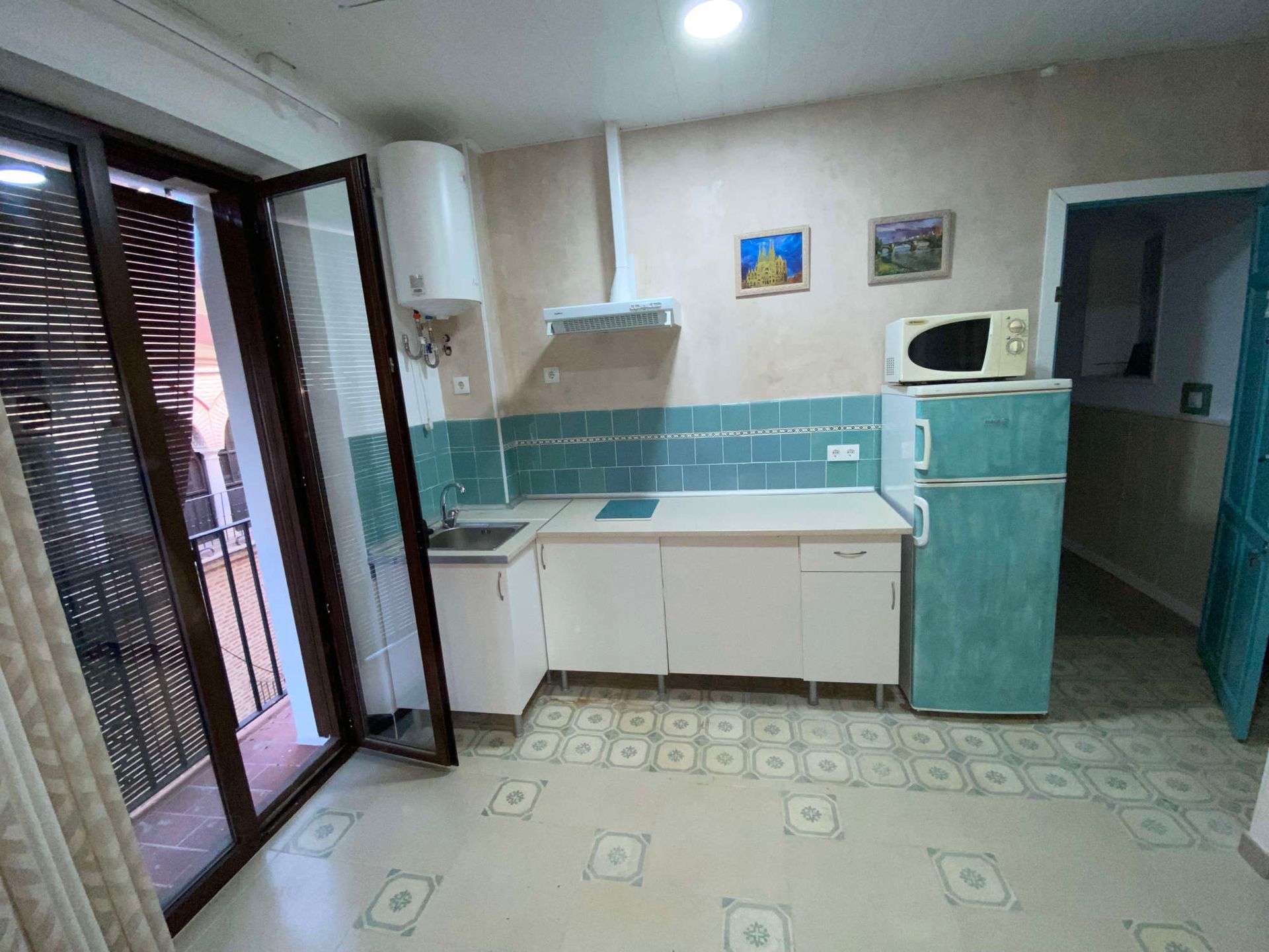 Una cocina con frigorífico, fregadero y microondas.