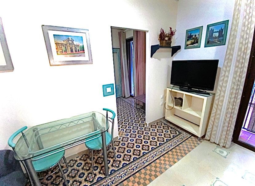 Una sala de estar con una mesa de cristal y sillas y un televisor de pantalla plana.