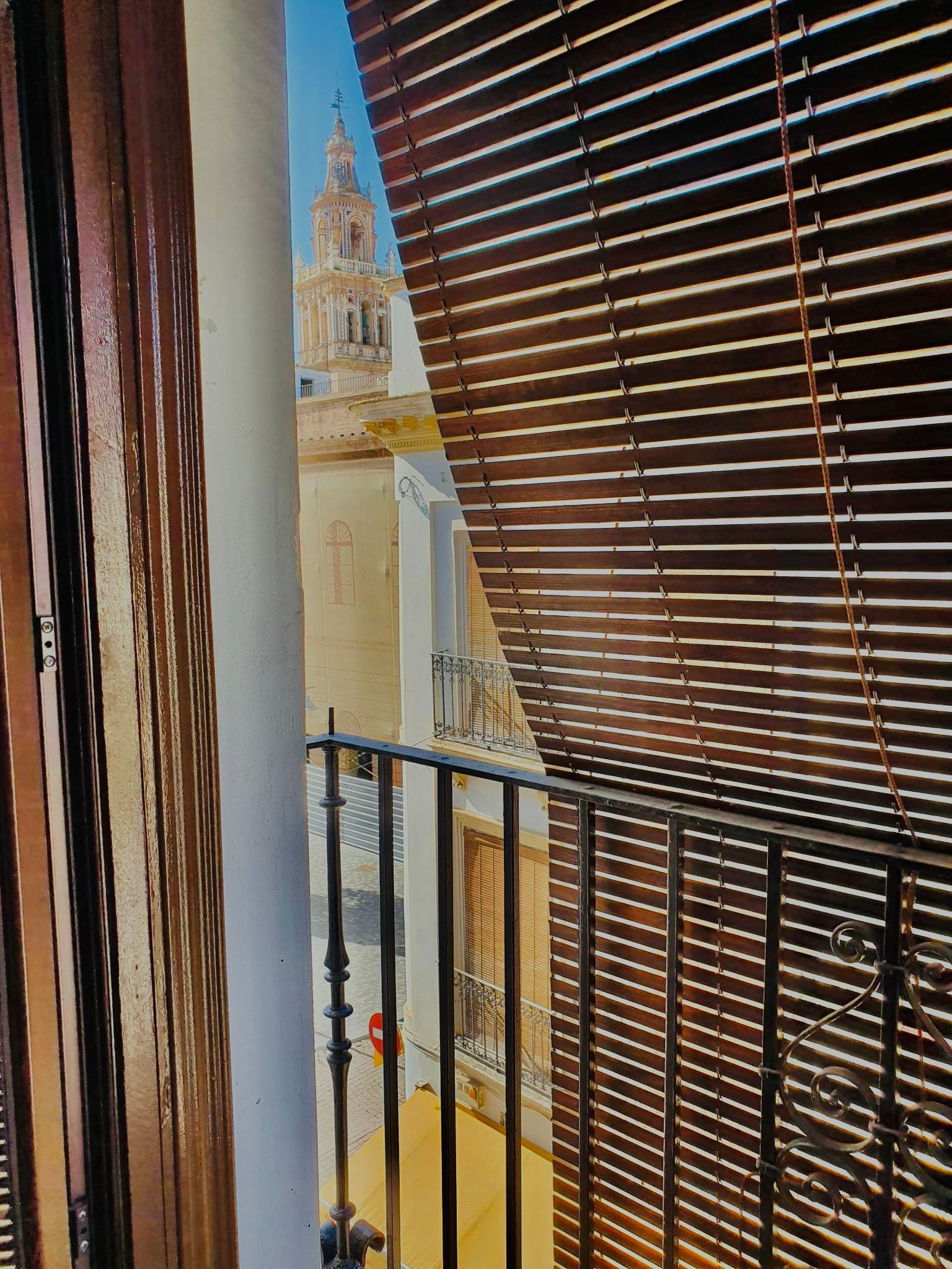 Un balcón con persianas de madera y vista a la ciudad.