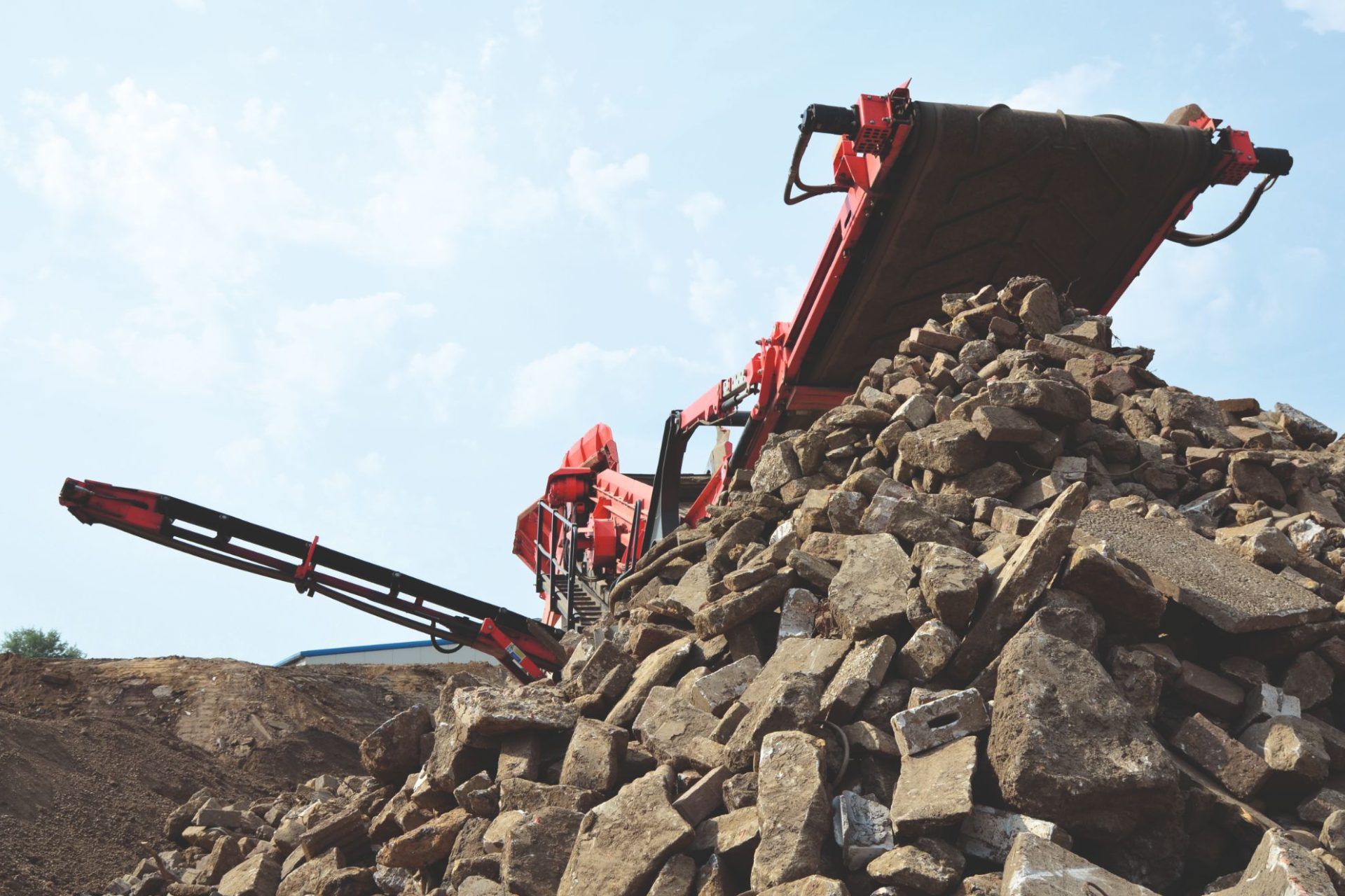 Rote Baumaschine hinter Steinhaufen