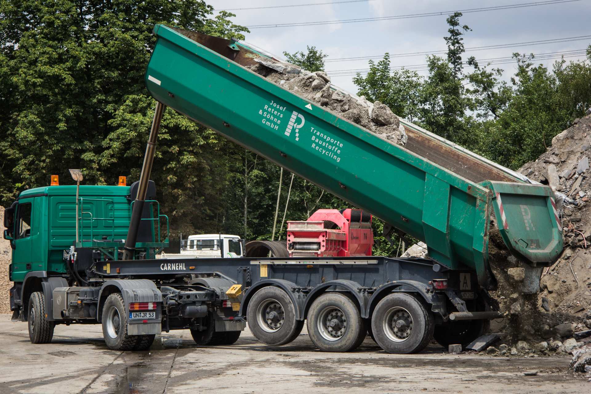 Grüner LKW mit Schüttlade, der Erde ablädt