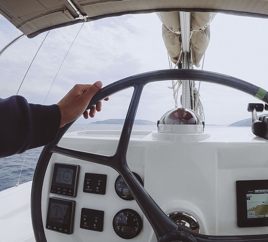 La mano de una persona está en el volante de un barco.
