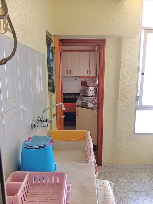Cocina pequeña con fregadero, paredes alicatadas, armarios y una ventana que deja entrar la luz natural.