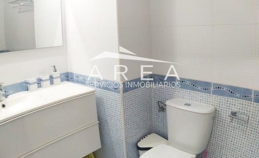 Baño pequeño con lavabo blanco, inodoro, espejo y azulejos azules en la pared.