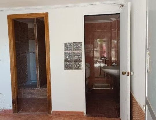 Pasillo interior con dos puertas de madera abiertas y un panel decorativo montado en la pared.