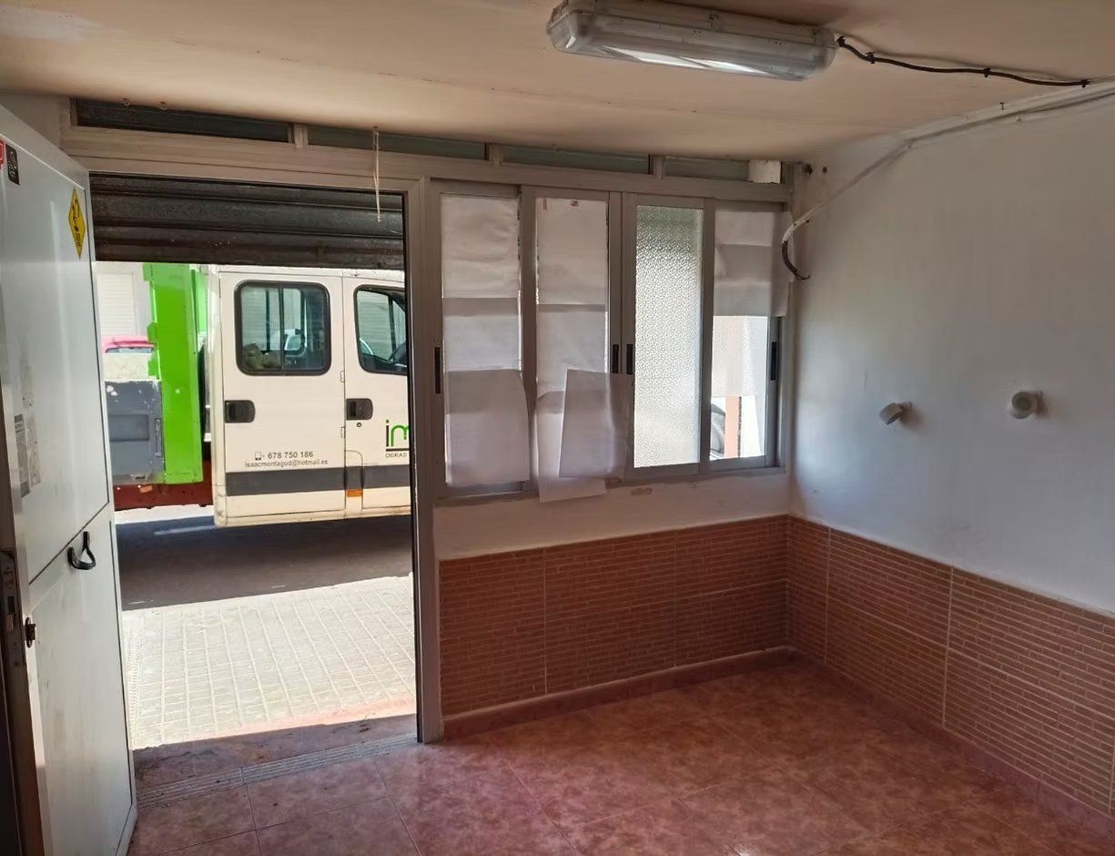 Habitación vacía con suelo de baldosas y ventana, con vistas a un tren aparcado fuera de la puerta.