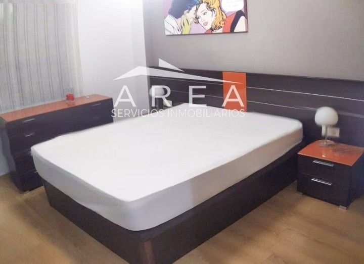 Dormitorio moderno con una cama grande, mesita de noche, lámpara y cuadros en la pared.