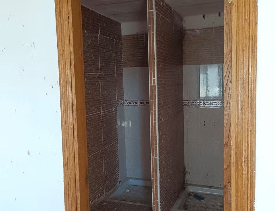 Baño pequeño con dos cabinas de ducha alicatadas y enmarcadas con molduras de madera.