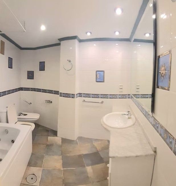 Baño pequeño con azulejos, bañera, inodoro, lavabo y ducha independiente.