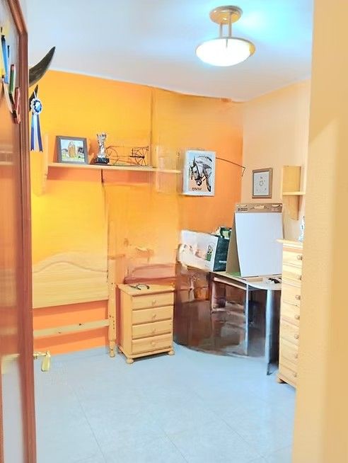 Oficina en casa de color naranja con escritorio, cajones, estantes y cuadros enmarcados.