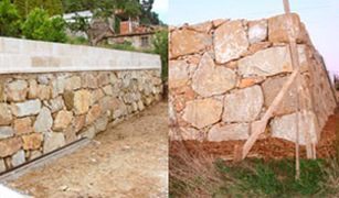 Se está construyendo un muro de piedra al lado de un camino de tierra.
