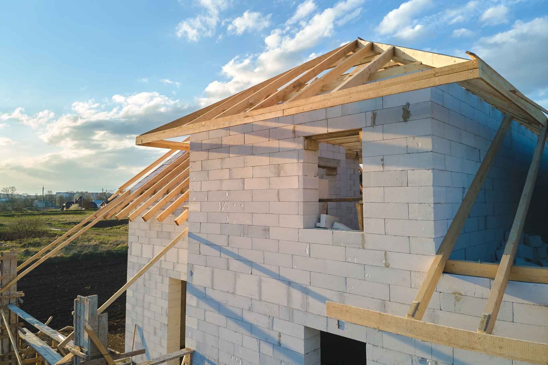 Se está construyendo una casa de ladrillo blanco con techo de madera.