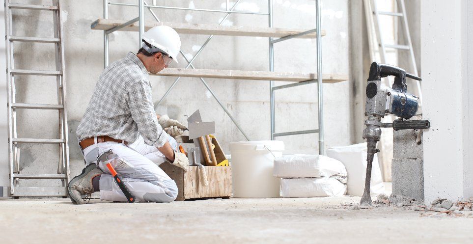 Un trabajador de la construcción está arrodillado en un edificio en construcción.
