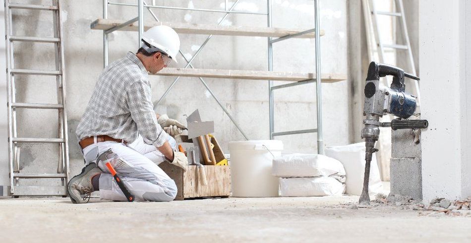 Un trabajador de la construcción está arrodillado en un edificio en construcción.