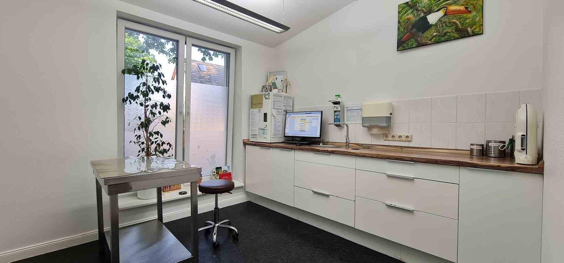 Eine Küche mit Tisch, Schränken, Computer und Fenster.