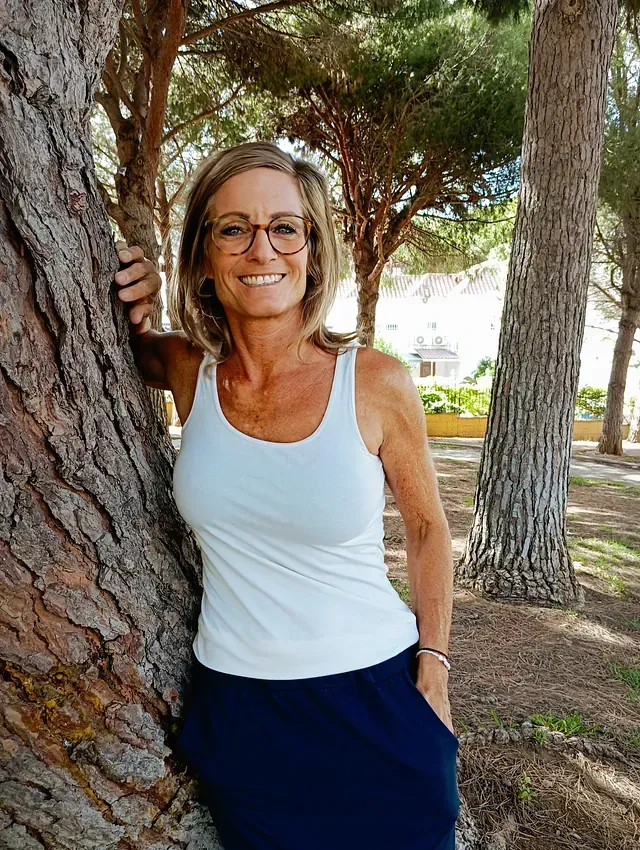 Una mujer está apoyada contra un árbol en un parque.