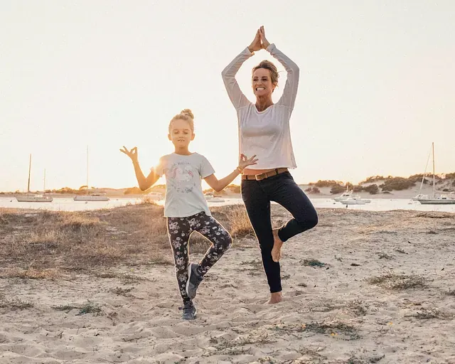 Una mujer y un niño están practicando yoga en la playa.