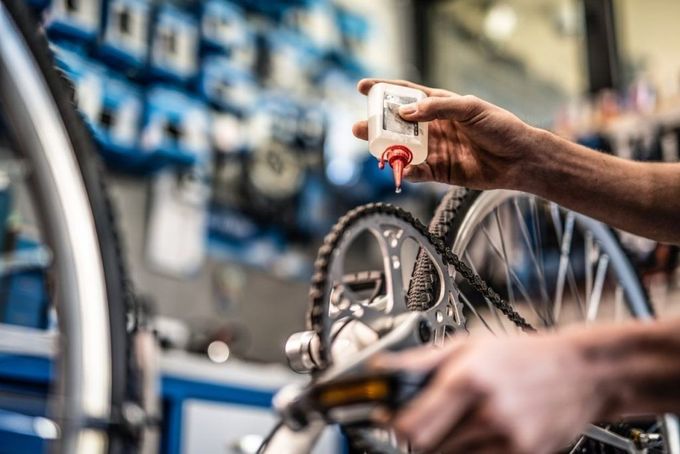 Una persona utiliza una herramienta para reparar una bicicleta, con varias llaves inglesas esparcidas por el suelo cerca.