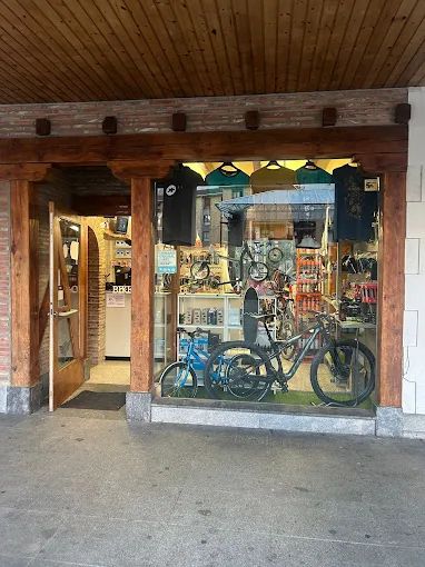 Un escaparate con estructura de madera rústica, que muestra una tienda de bicicletas a través de un gran ventanal.