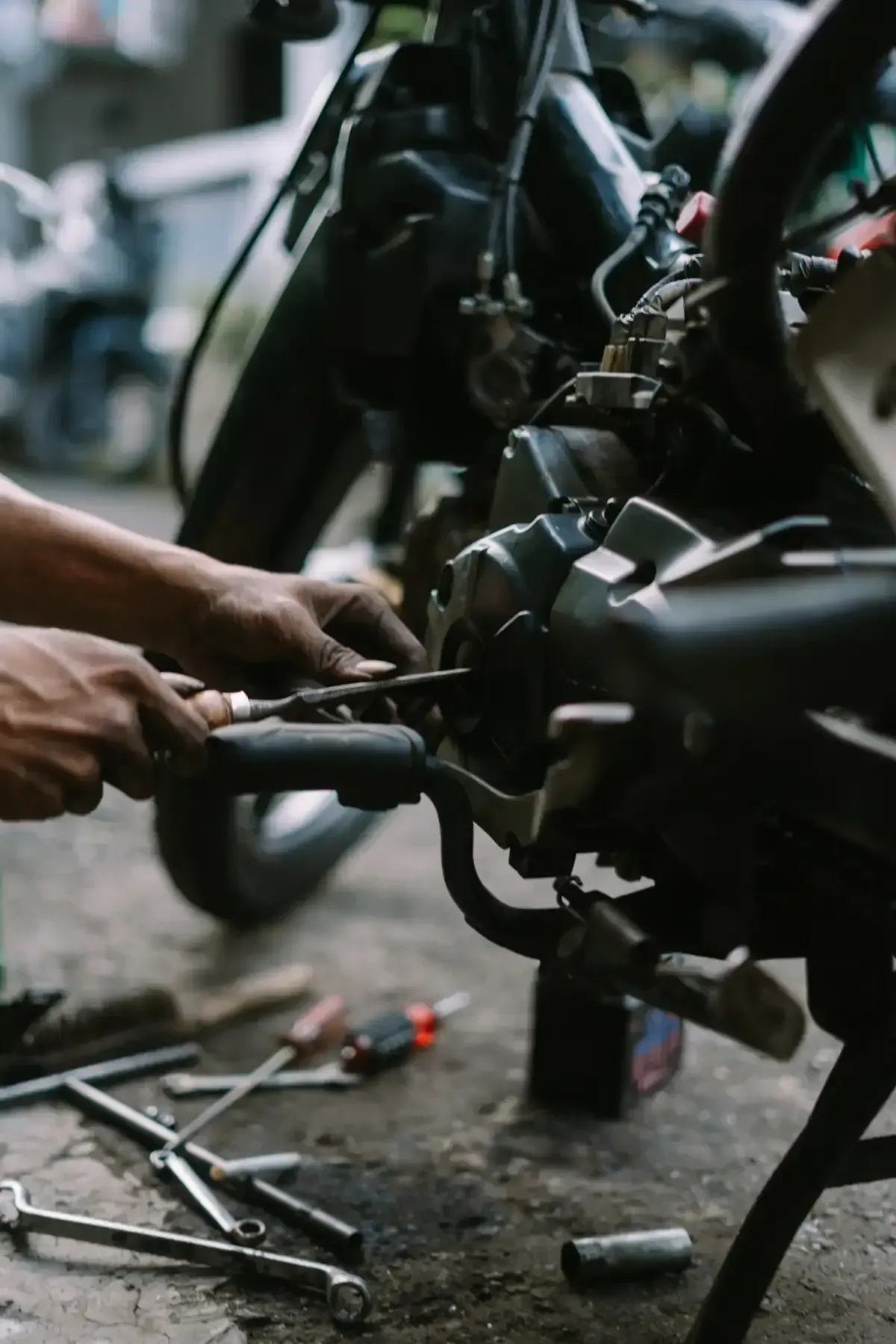 Una persona utiliza una herramienta para reparar una bicicleta, con varias llaves inglesas esparcidas por el suelo cerca.