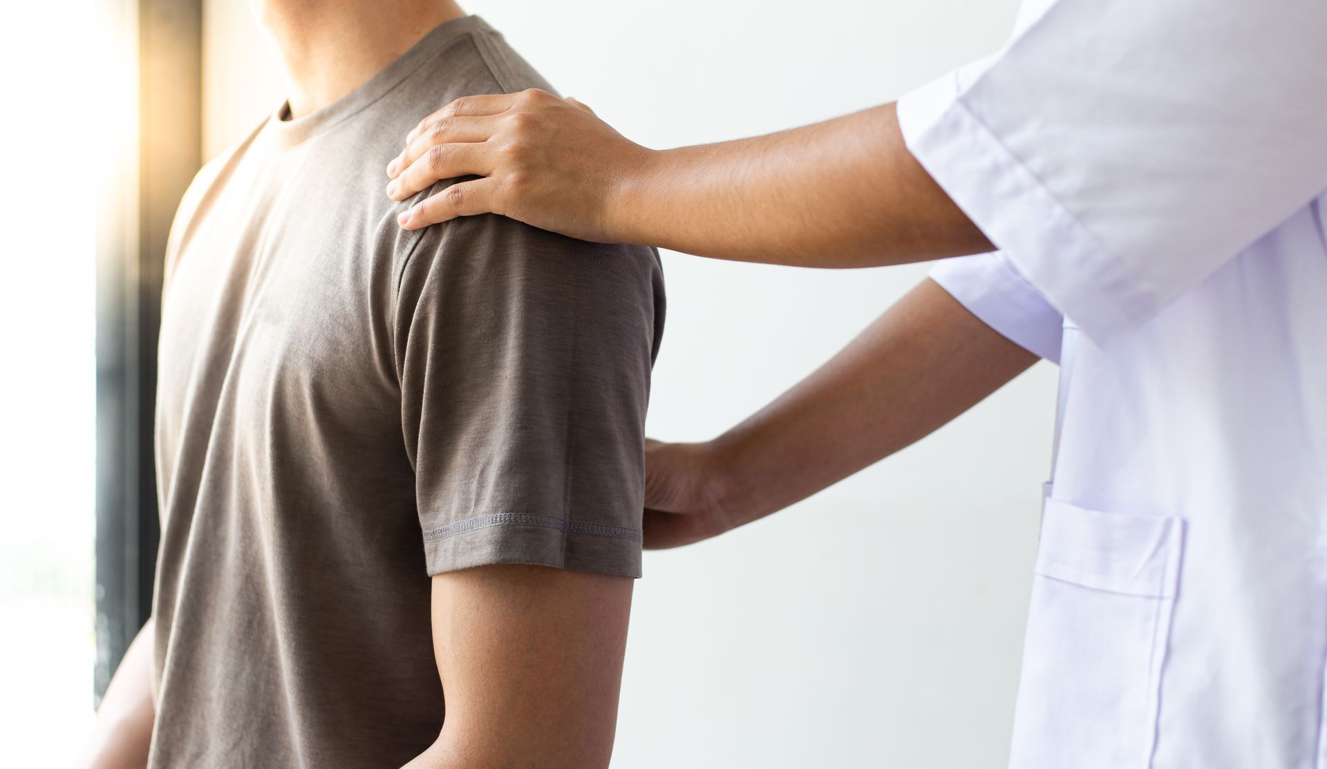 Ein Physiotherapeut führt in einer klinischen Umgebung eine Justierung am unteren Rücken eines Patienten durch.