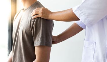 Ein Physiotherapeut führt in einer klinischen Umgebung eine Justierung am unteren Rücken eines Patienten durch.