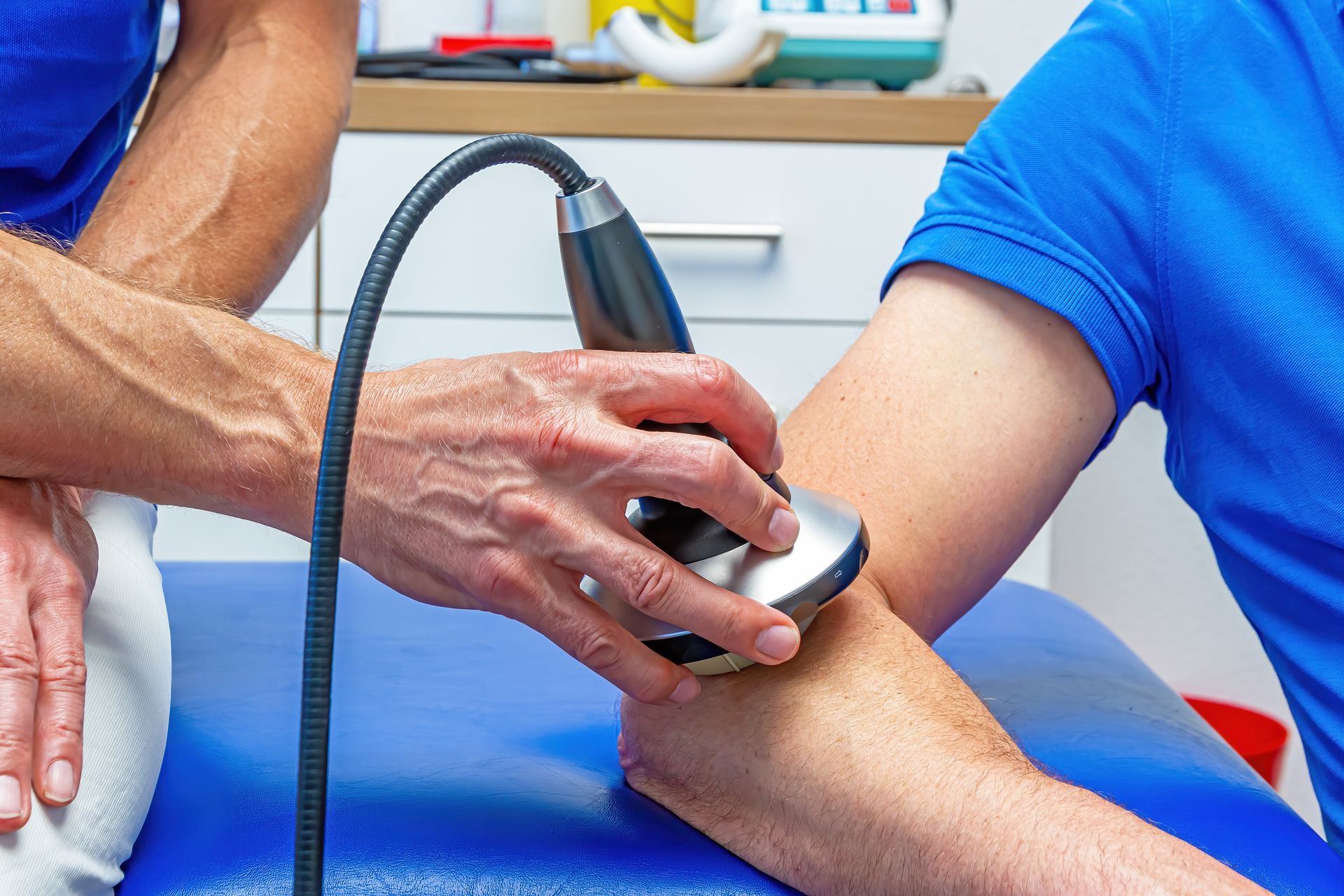 Eine Person führt in einem Fitnessstudio eine Kniebeuge mit der Langhantel aus und hält dabei eine beschwerte Stange mit einem Nackenpolster über den Schultern.