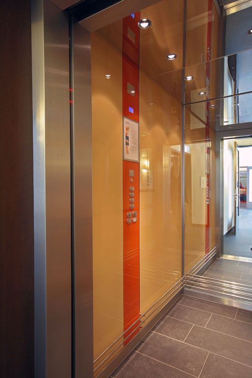 Ein Flur mit Glaswand und Edelstahlaufzug
