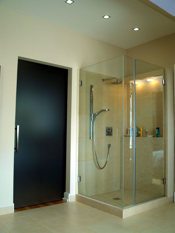 Ein Badezimmer mit einer Glasdusche und einer schwarzen Tür