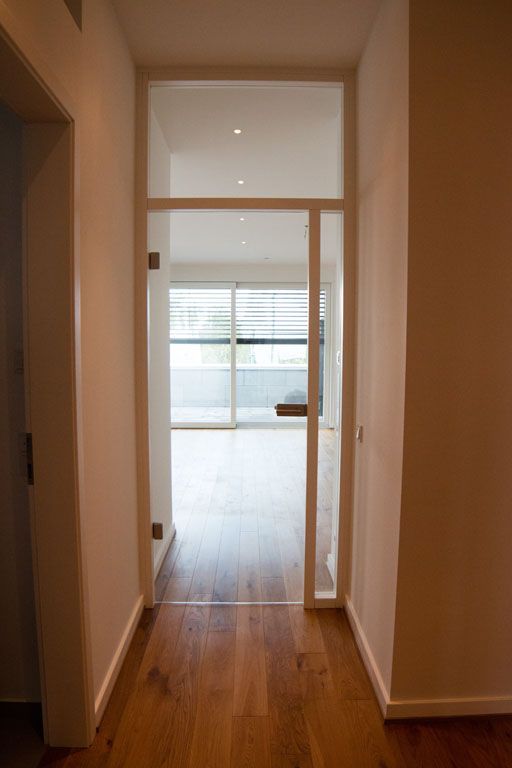 Ein Flur mit einer Glastür, die zu einem Wohnzimmer führt