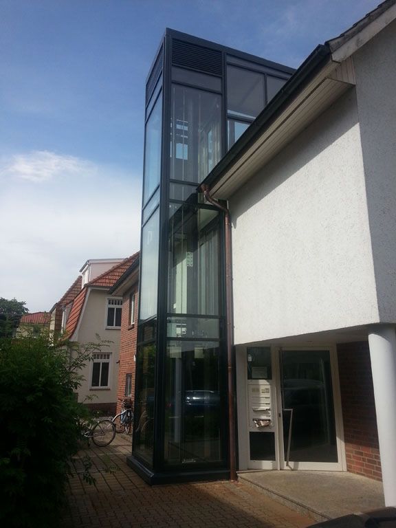 Ein weißes Gebäude mit einem großen Glasaufzug an der Seite