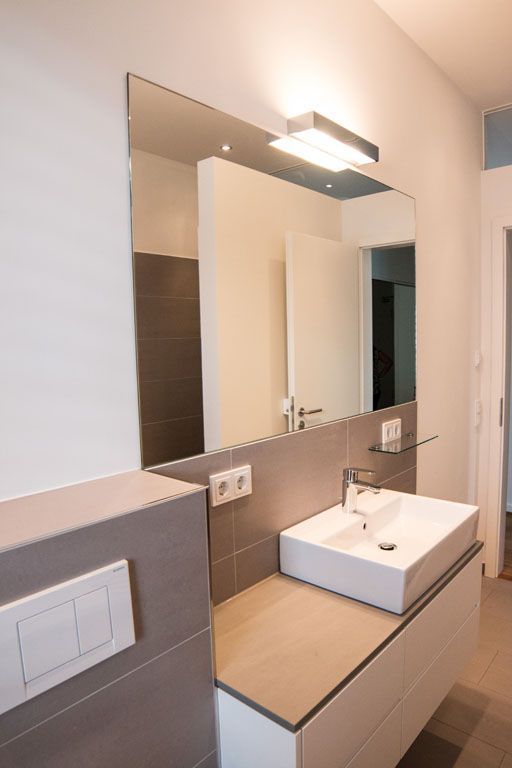 Ein Badezimmer mit Waschbecken und großem Spiegel