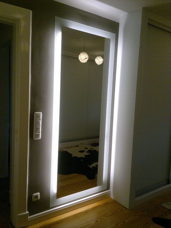 In einem Flur ist ein Ganzkörperspiegel beleuchtet