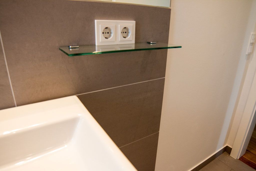 Ein Badezimmer mit einem Waschbecken und einem Glasregal darüber