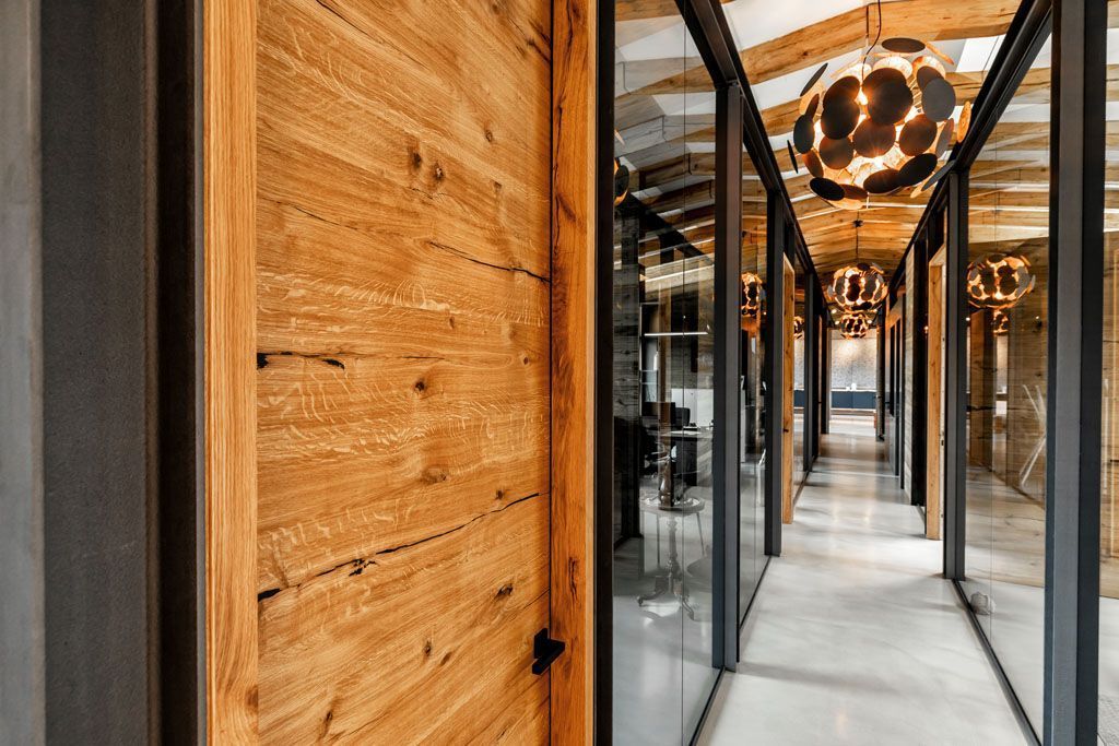 Ein langer Flur mit einer Holztür und Glaswänden.