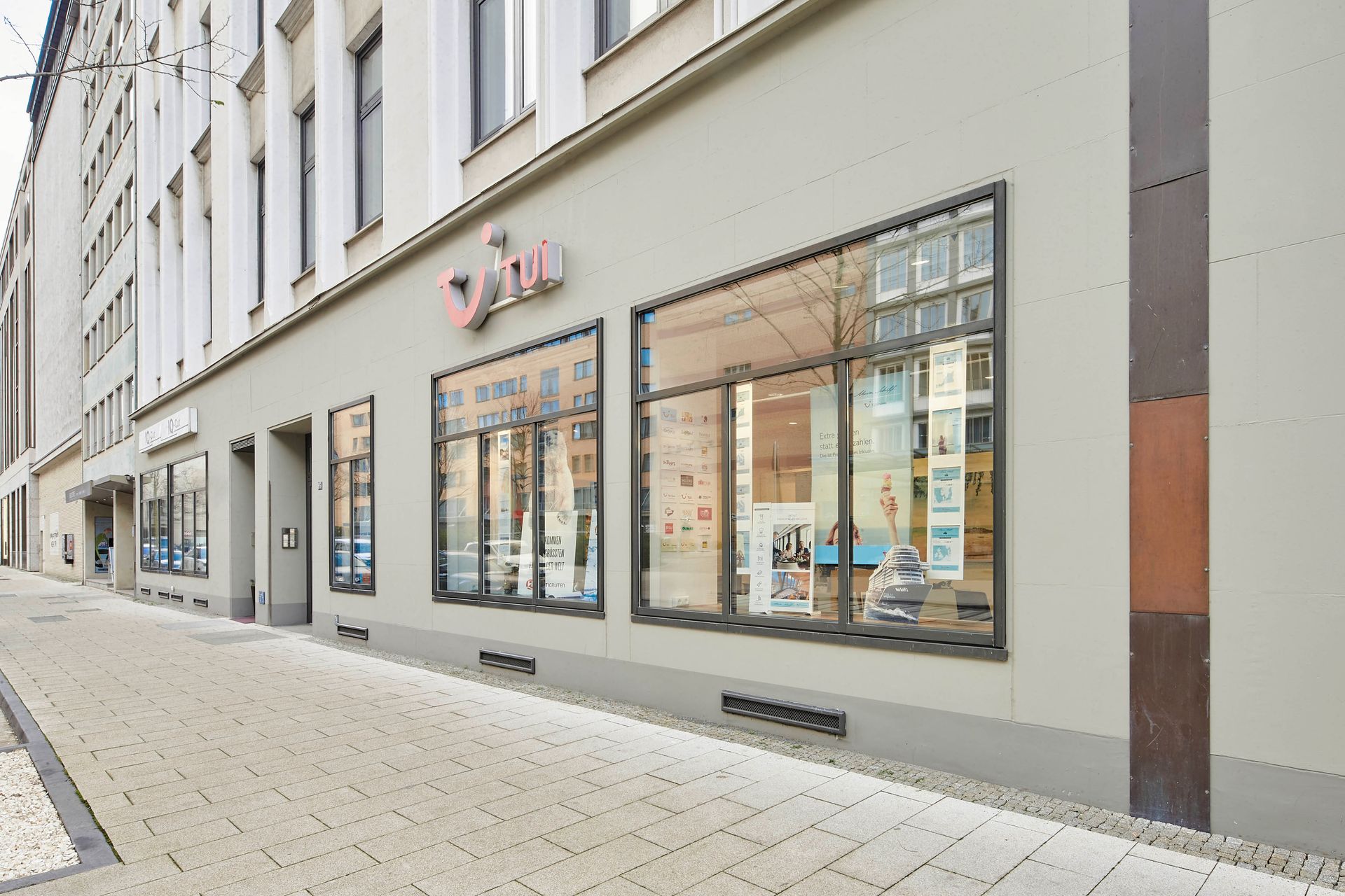 Ein Gebäude mit vielen Fenstern und einem Backsteingehweg davor.