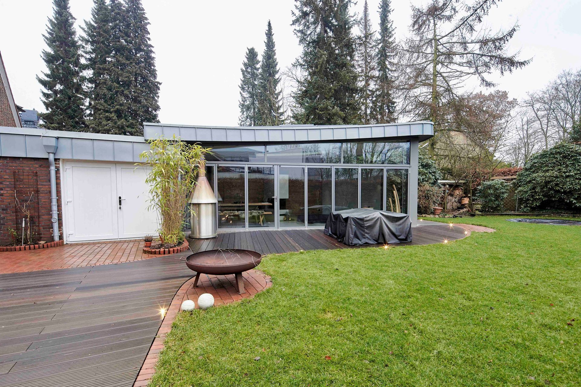 Ein Haus mit großer Wiese und einer Feuerstelle davor.