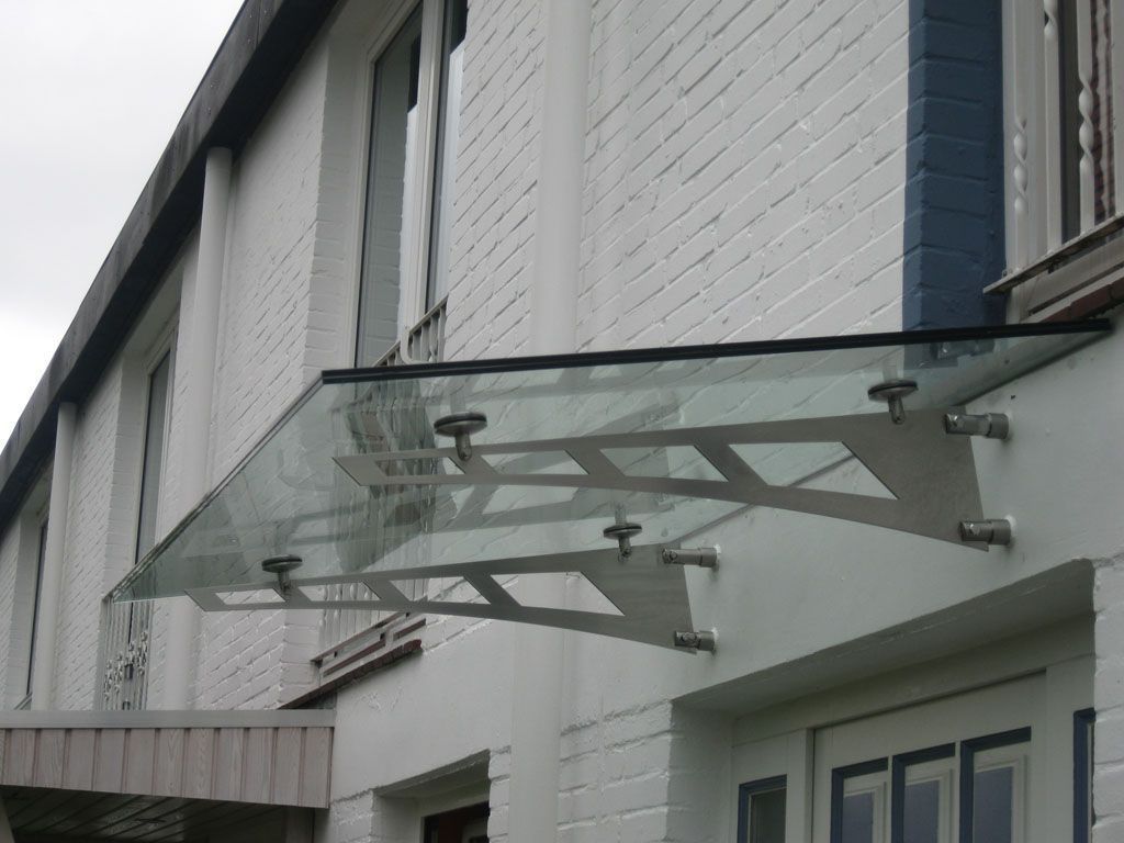 Ein weißes Backsteingebäude mit einem Glasdach über der Tür