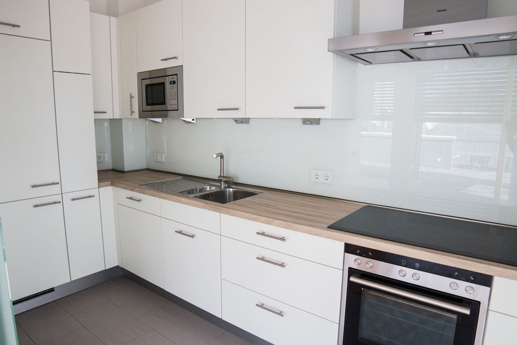 Eine Küche mit weißen Schränken und Geräten aus Edelstahl